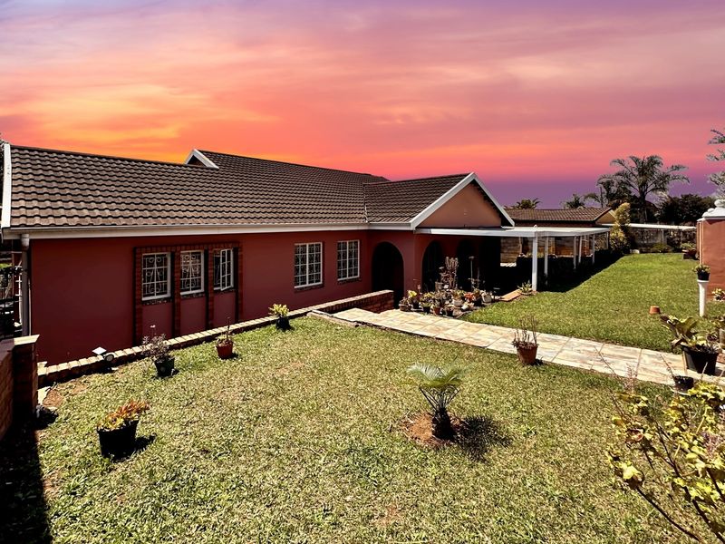 A view of the rear exterior of the house featuring a tiled roof, brick facade, paved walkway, and a well-maintained lawn.