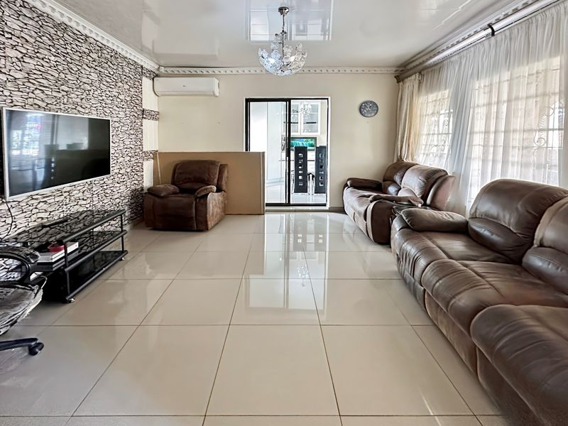 Spacious living room featuring large format floor tiles, a textured stone feature wall, and a split-system air conditioning unit.