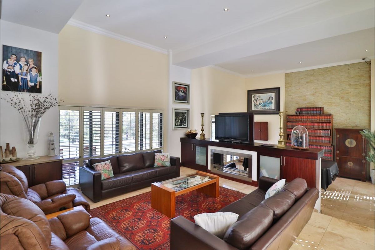 Spacious living room featuring high ceilings, recessed lighting, tiled flooring, and a built-in fireplace partition with integrated cabinetry.