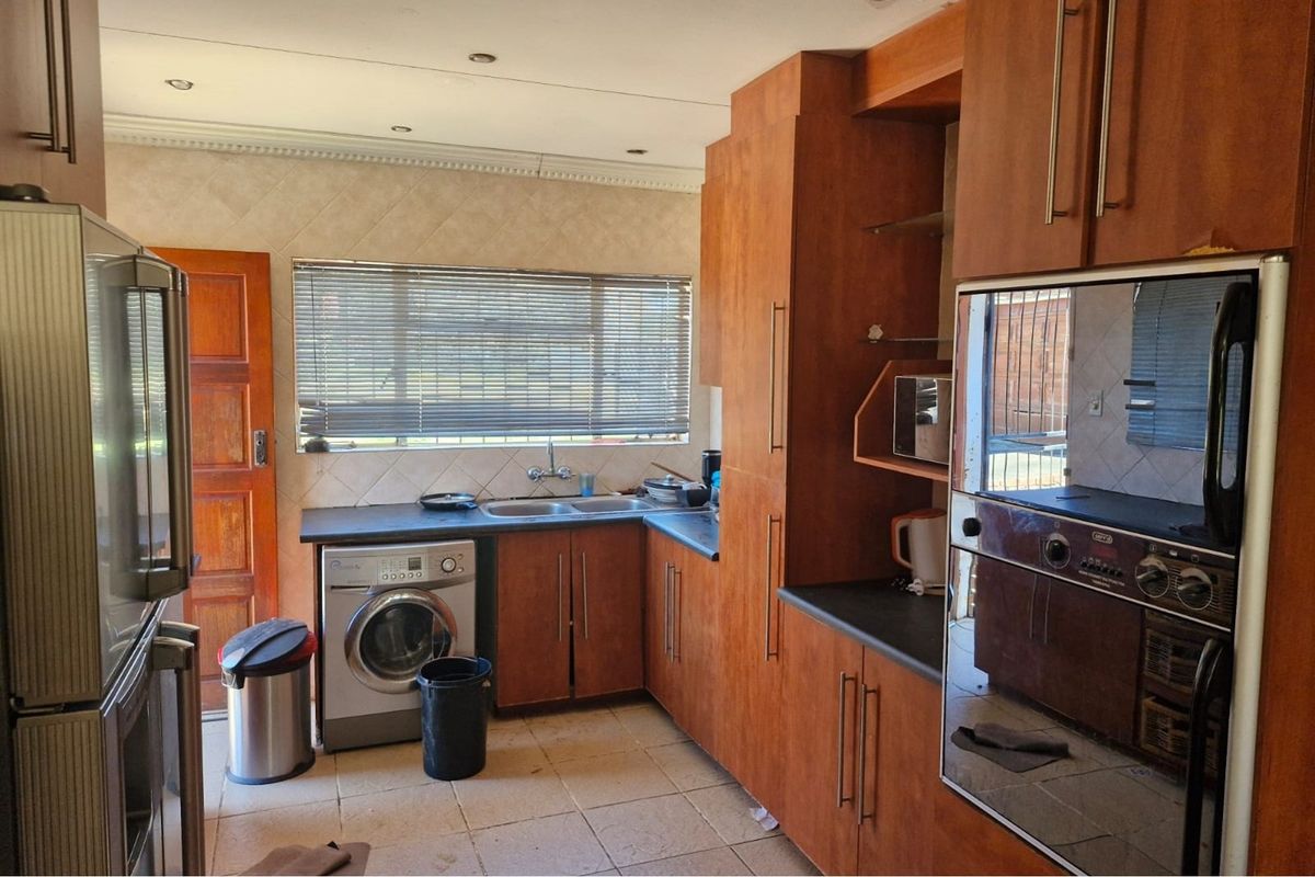 A functional kitchen featuring wood-finish cabinetry, laminate countertops, a double basin sink, and a built-in oven, with tiled flooring throughout.