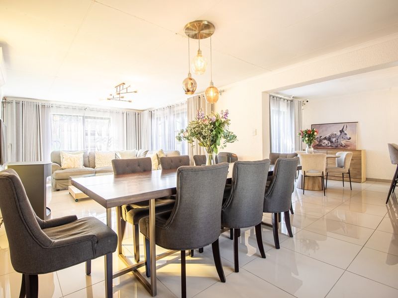 Spacious open-plan living and dining area featuring polished porcelain floor tiles, modern pendant lighting, and a split-system air conditioner.