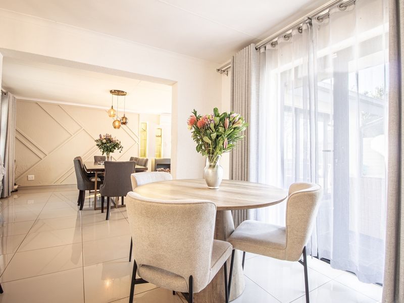 Bright open-plan living and dining area featuring polished tile flooring, decorative wall paneling, and large sliding glass doors providing natural light.