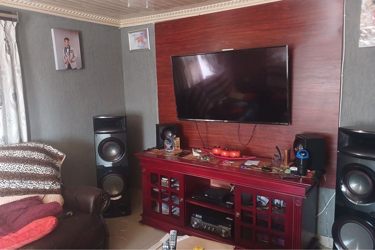 A living room featuring a wood-paneled feature wall with a mounted television and a decorative ceiling finish.