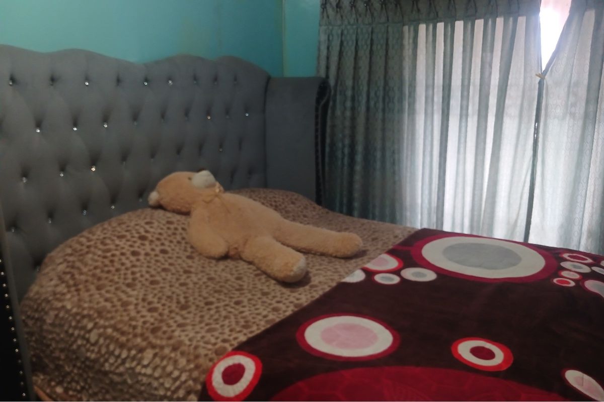 A bedroom featuring a tufted upholstered headboard and window treatments.