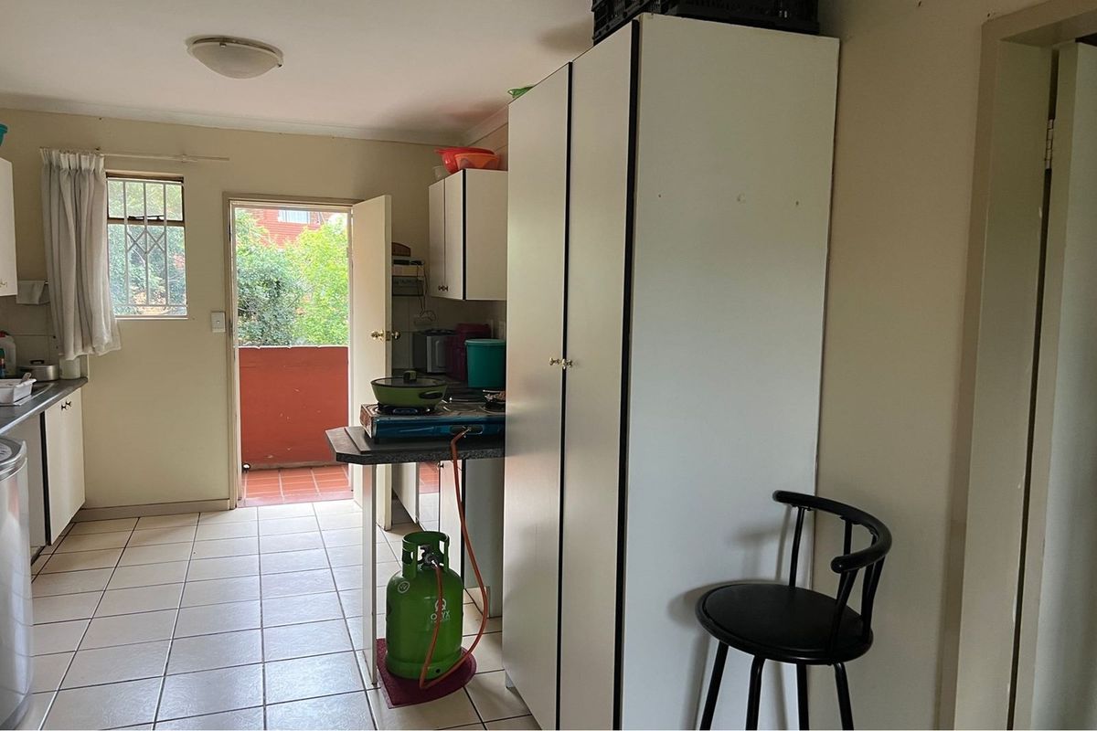 A functional kitchen area featuring tiled flooring, built-in cabinetry, and direct access to an outdoor balcony space.