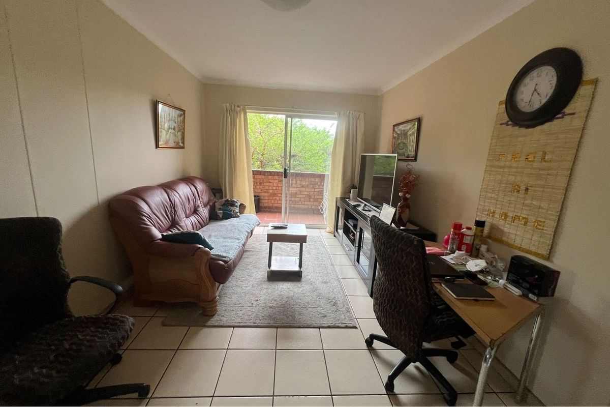 A living room featuring tiled flooring and a sliding glass door that opens onto a private balcony.