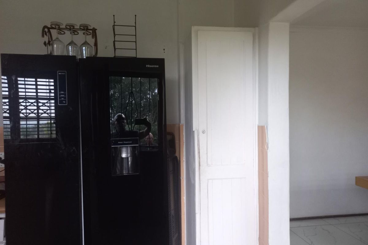 A kitchen area featuring a built-in pantry cupboard and tiled flooring, providing functional storage space within the home.