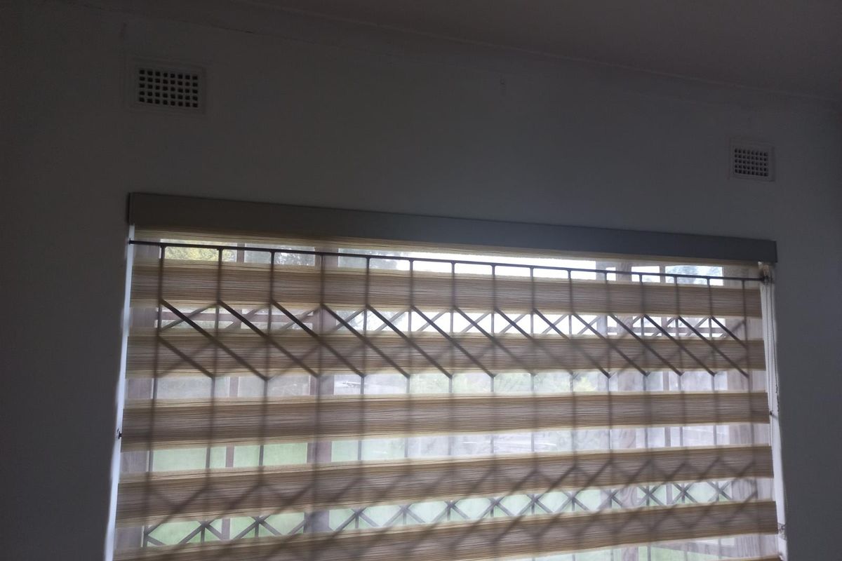 A view of a window featuring installed security bars and ventilation grilles in a neutral-toned room.