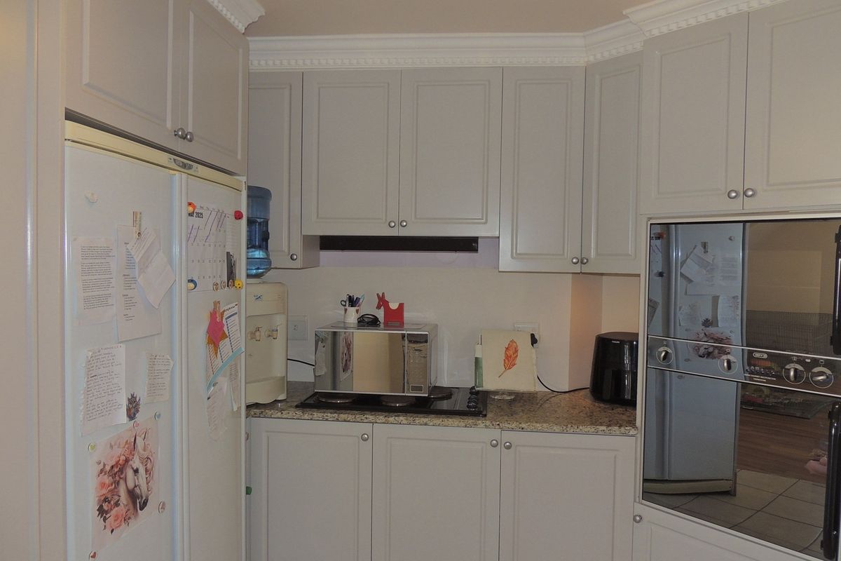 A functional kitchen featuring light-toned cabinetry, granite countertops, a built-in oven, and a cooktop with an integrated extractor fan.