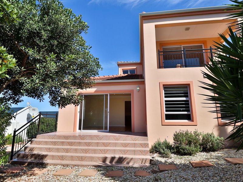 Rear view of the property featuring a tiled patio, sliding glass doors, and an upper-level balcony with metal railings.