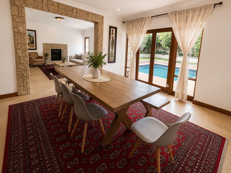 Spacious open-plan dining and living area featuring a stone-clad archway, a stone fireplace, and sliding glass doors opening to a swimming pool.