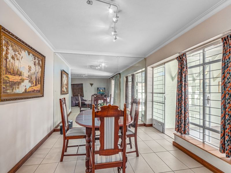 Dining room featuring tiled flooring, a large mirrored wall, and sliding glass doors providing access to the exterior.
