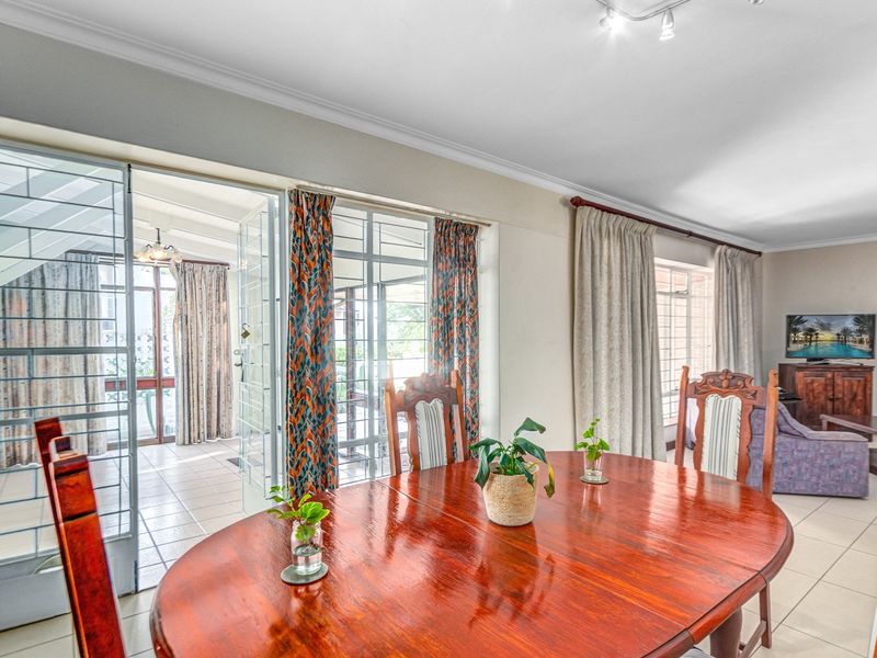 Open-plan living and dining area featuring tiled flooring, security gates, and direct access to an adjoining patio space.