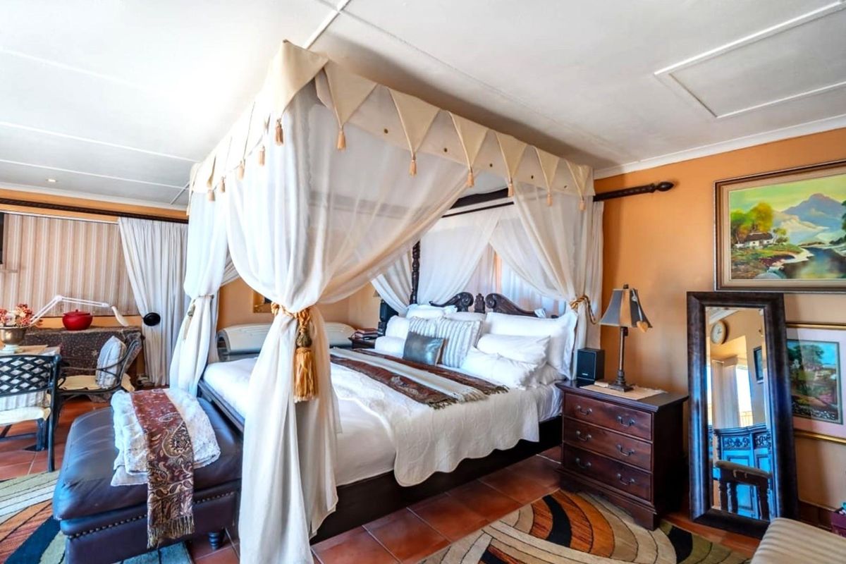 Spacious bedroom featuring terracotta floor tiles and a classic four-poster bed frame.