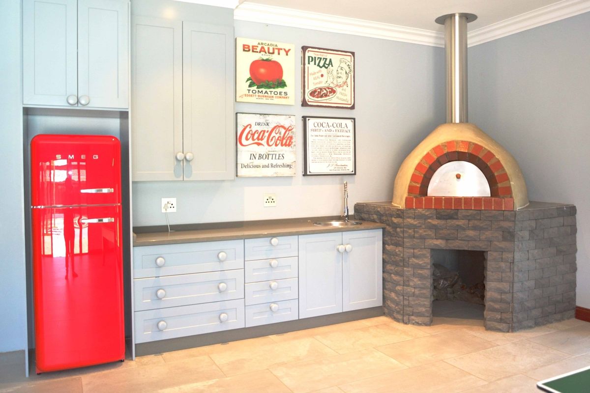 A well-maintained kitchen area featuring custom cabinetry, stone countertops, an integrated sink, and a prominent built-in stone pizza oven.