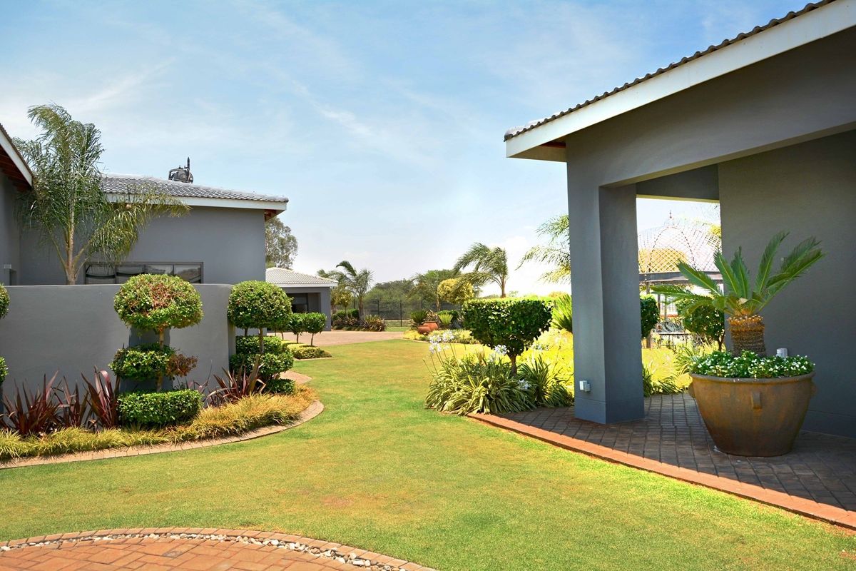 A well-maintained rear garden area featuring a paved patio, manicured lawn, and modern grey exterior building finishes.