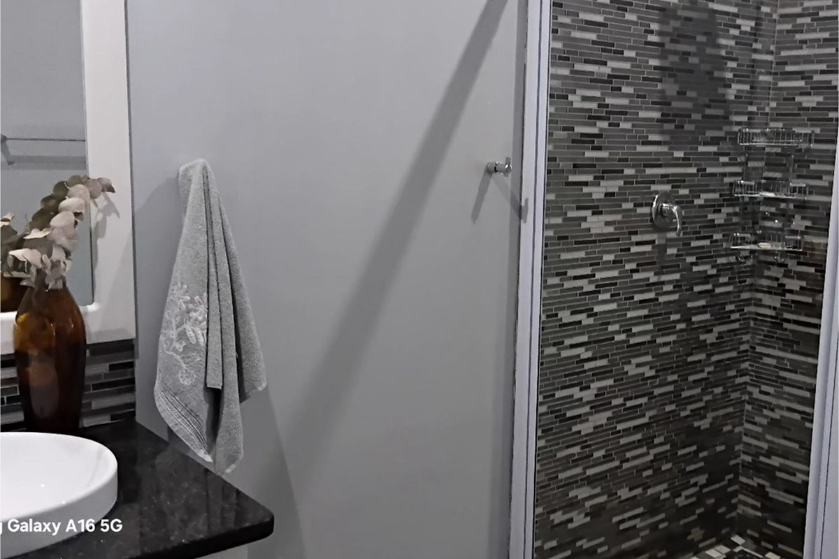 A modern bathroom featuring a walk-in shower with decorative mosaic tile wall cladding and a vanity with a countertop basin.
