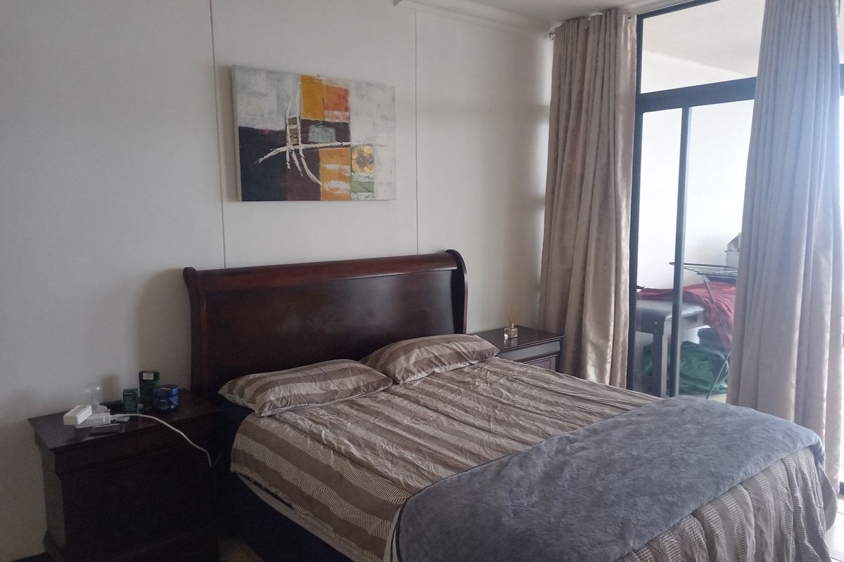 A well-lit bedroom featuring large sliding glass doors that provide access to an adjoining balcony, allowing for ample natural light.
