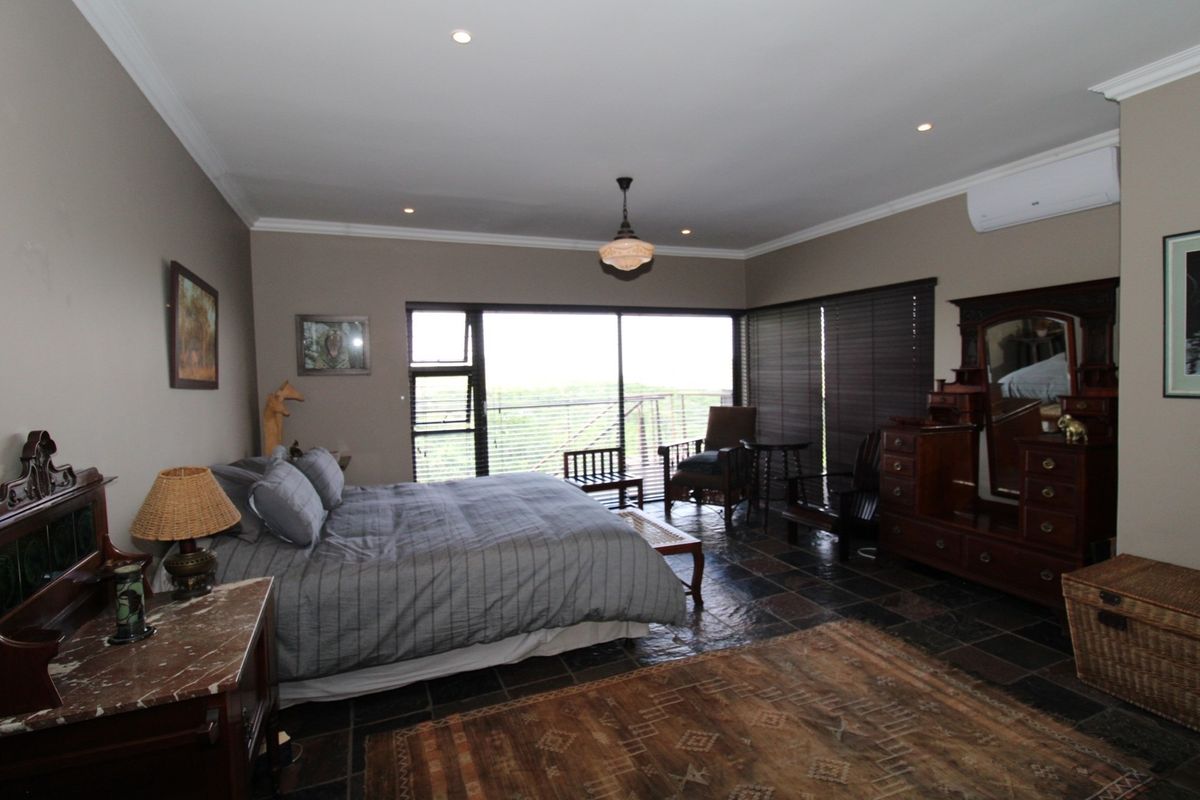 Spacious bedroom featuring dark slate tile flooring, recessed lighting, a wall-mounted air conditioning unit, and large sliding glass doors leading to an outdoor area.