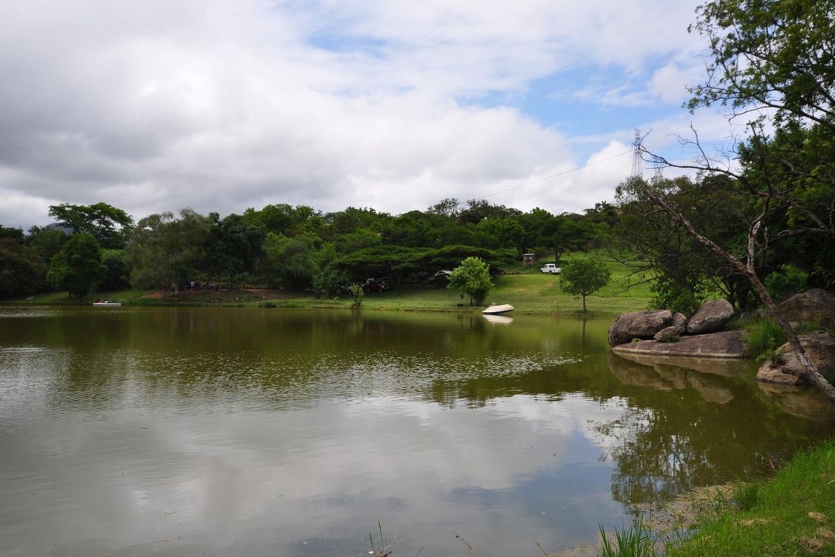 A scenic view of a tranquil lake surrounded by lush greenery and natural rock formations on the property grounds.