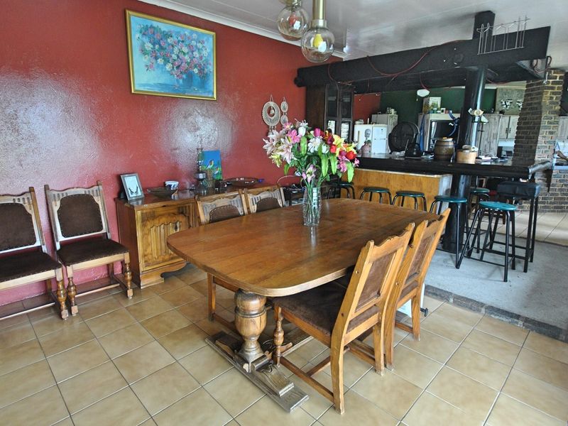 Open-plan dining and kitchen area featuring tiled flooring, a breakfast bar, and a prominent red feature wall.