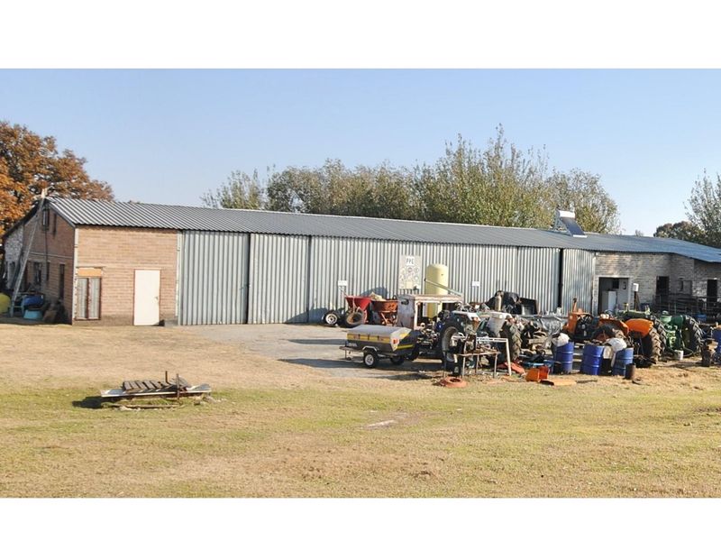 Large agricultural shed or farm utility building featuring corrugated metal cladding and brickwork, situated on a spacious rural property.