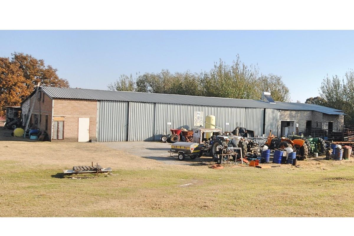 Large agricultural shed or farm utility building featuring corrugated metal cladding and brickwork, situated on a spacious rural property.