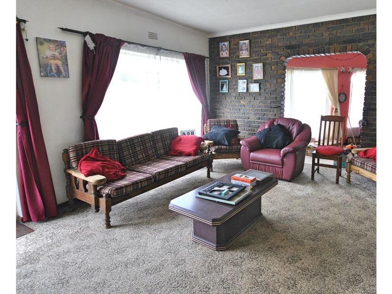 A living room featuring a prominent exposed brick feature wall and an arched entryway leading to an adjacent space.