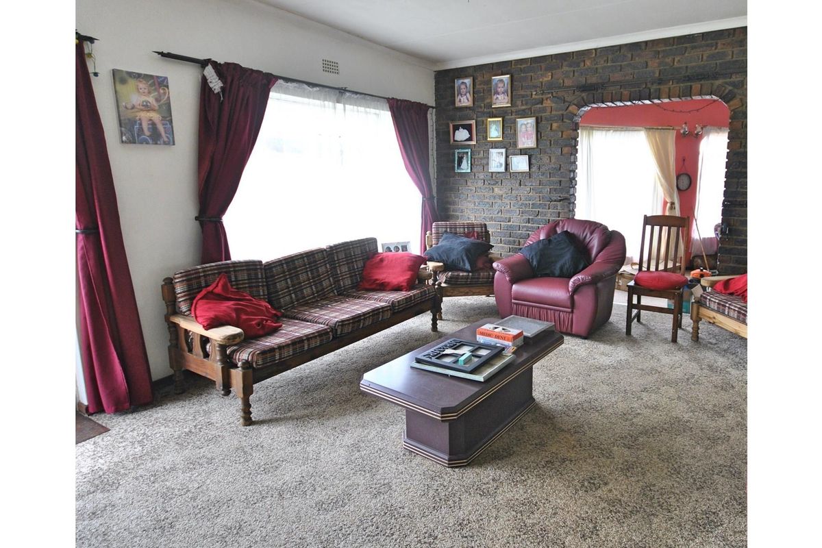 A living room featuring a prominent exposed brick feature wall and an arched entryway leading to an adjacent space.