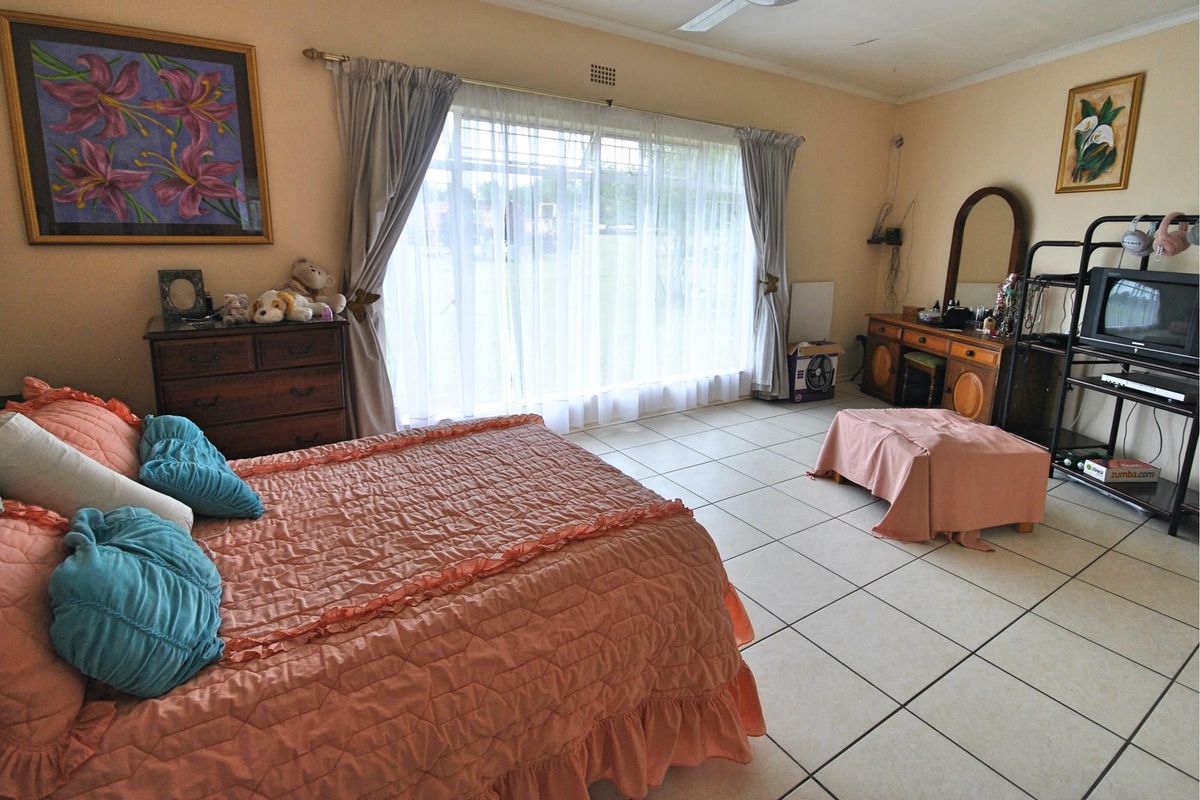 Spacious bedroom featuring large windows with natural light, tiled flooring, and a ceiling fan.