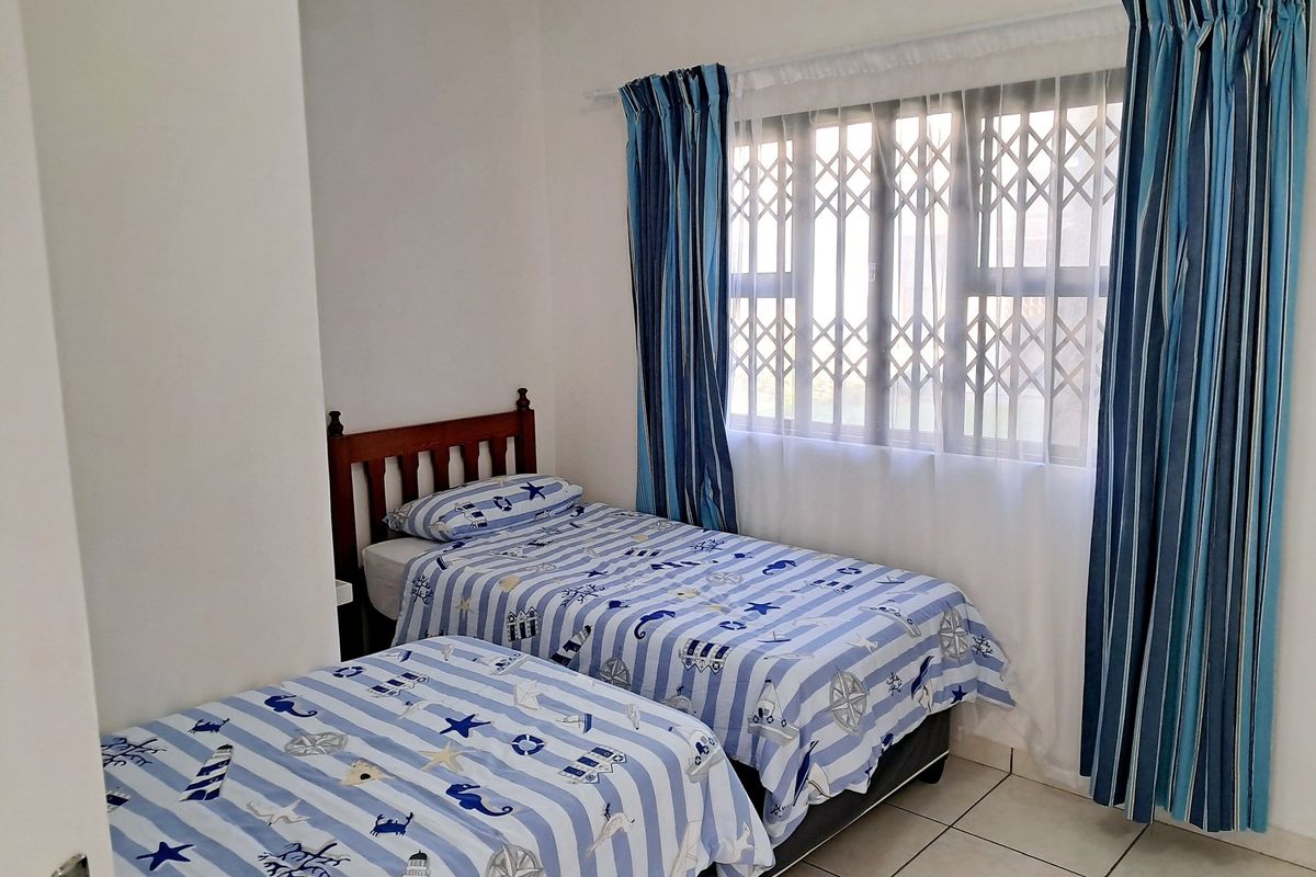 A functional bedroom featuring tiled flooring and a window fitted with a security gate.