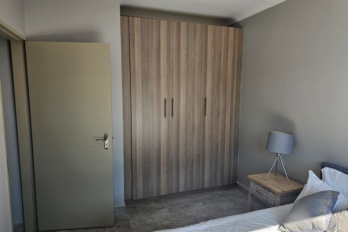 A bedroom featuring built-in wooden cabinetry and tiled flooring, providing ample storage space.