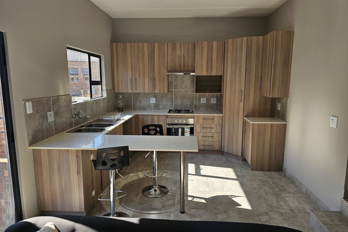 Modern kitchen featuring wood-grain cabinetry, stone countertops, a built-in oven, gas hob, extractor fan, and a breakfast nook extension.