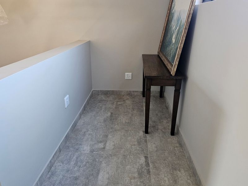 A compact hallway or landing area featuring neutral wall finishes and modern grey tiled flooring with integrated electrical outlets.