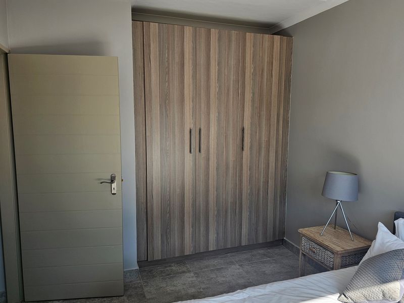 A bedroom featuring built-in wooden cabinetry and tiled flooring, providing ample storage space.