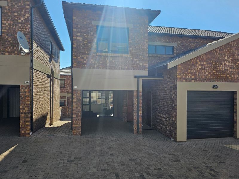 A modern face-brick apartment exterior featuring a paved driveway, single garage, and covered entrance area.