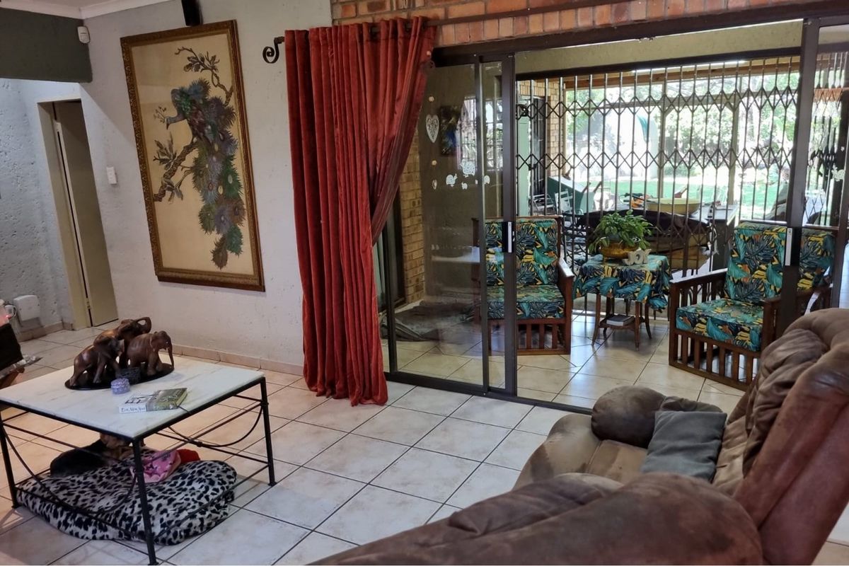 Living room featuring tiled flooring and large sliding glass doors providing direct access to a covered patio area.