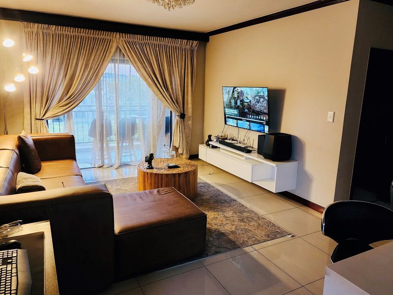 A comfortable living room featuring tiled flooring, crown molding, and a sliding glass door providing access to an outdoor balcony area.