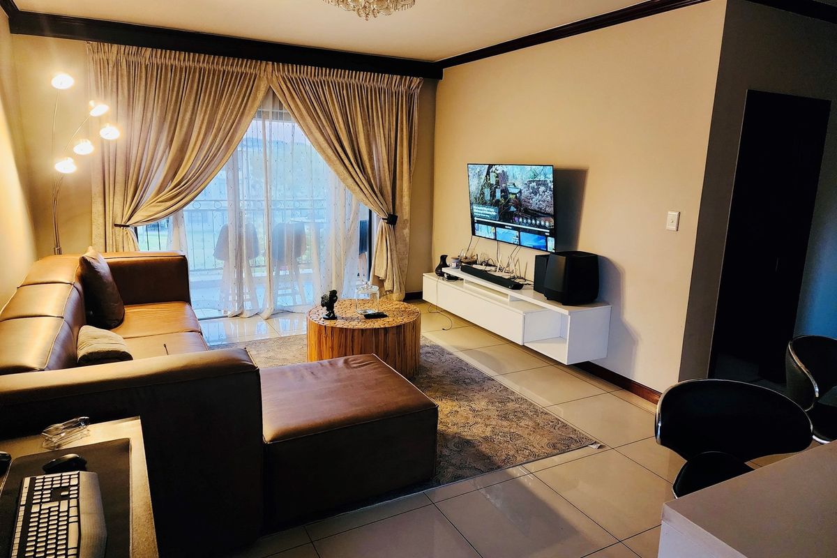 A comfortable living room featuring tiled flooring, crown molding, and a sliding glass door providing access to an outdoor balcony area.