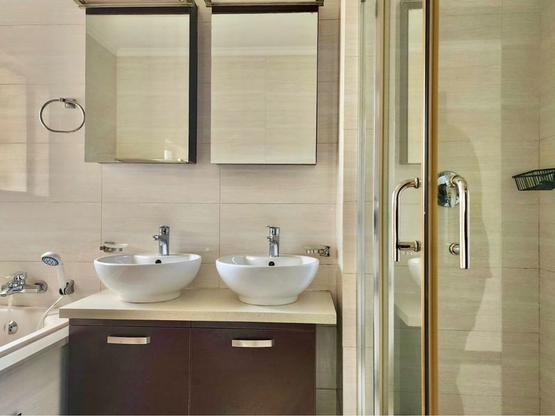 Modern bathroom featuring a double vanity with vessel sinks, medicine cabinets, a separate shower enclosure, and a bathtub with neutral wall tiling.
