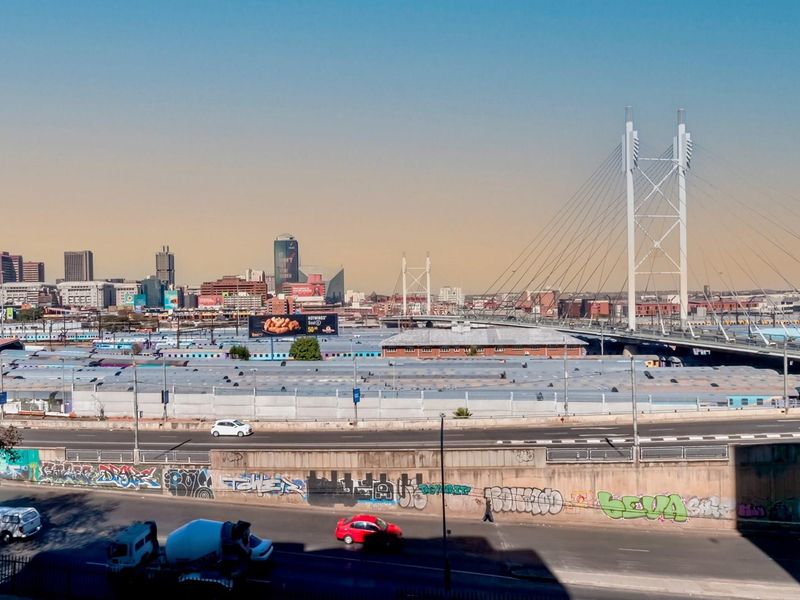 An elevated urban view overlooking a major bridge, railway infrastructure, and the city skyline.