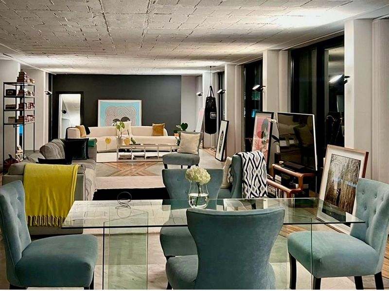 Spacious open-plan living and dining area featuring a unique exposed concrete block ceiling, large windows, and modern industrial aesthetic.