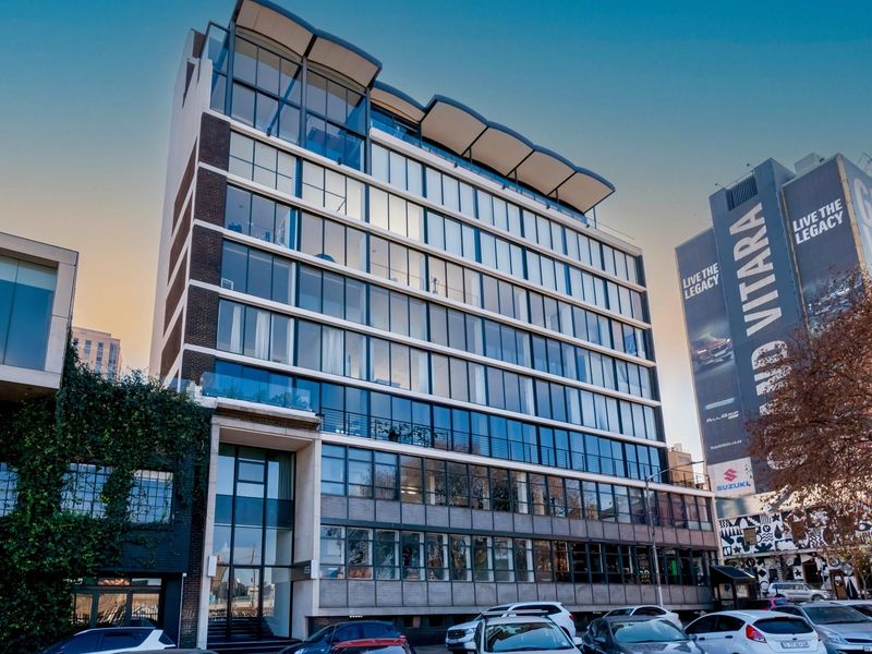 Modern multi-story apartment building featuring a glass facade, contemporary architectural design, and prominent street-level entrance.