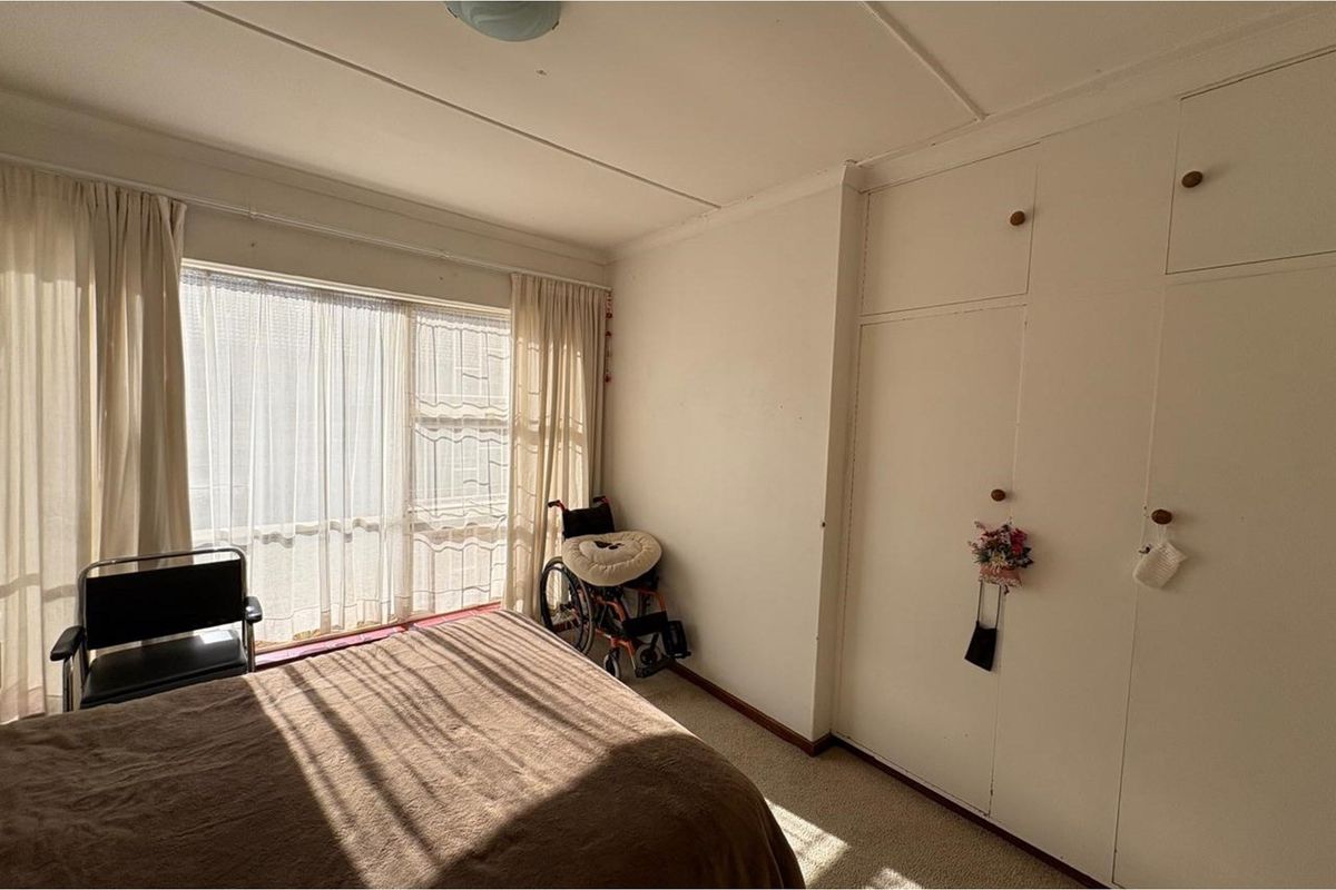 A bedroom featuring built-in cupboards and large windows allowing for natural light.