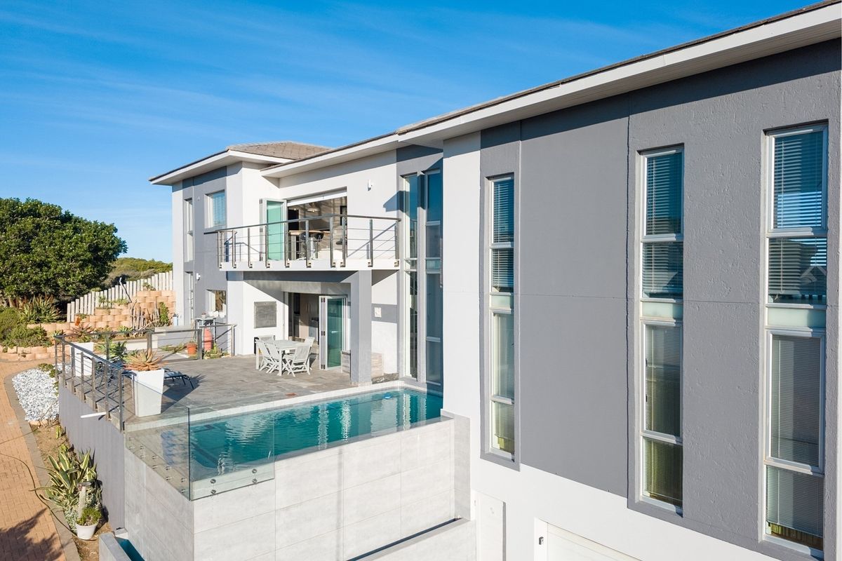 Modern multi-level residence featuring a sleek swimming pool, spacious patio area, and contemporary architectural design with large windows and a balcony.