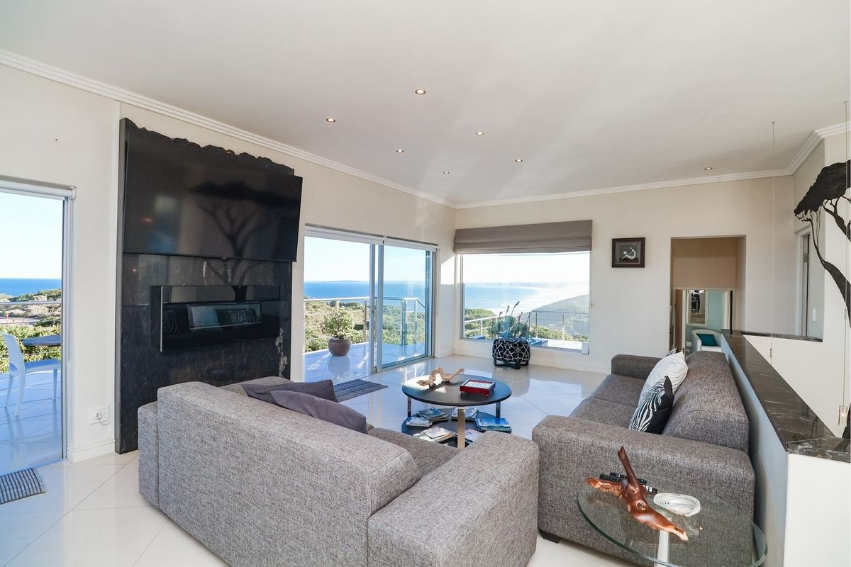Spacious living room featuring a modern stone-clad fireplace, large sliding glass doors, and expansive ocean views, leading out to a private balcony.