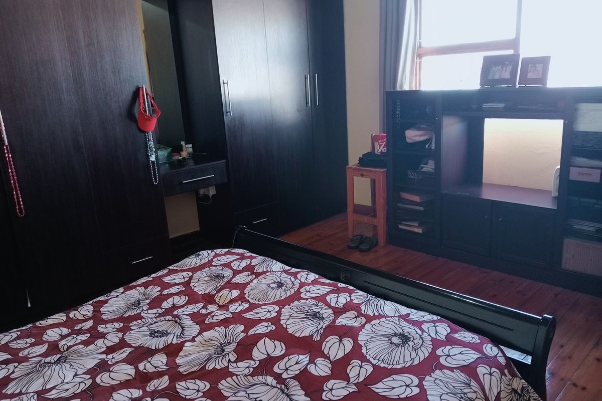 A bedroom featuring dark wood-toned built-in cabinetry and warm timber flooring, providing ample storage space and a classic aesthetic.