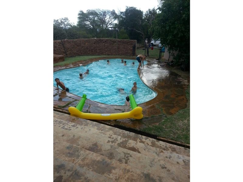 Outdoor swimming pool area featuring natural stone paving and a stone boundary wall, set within a rural farm landscape.