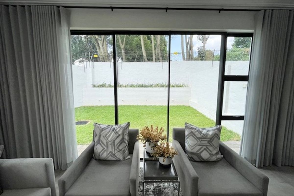 A bright living area featuring large sliding glass doors that provide a seamless transition to a private, well-maintained rear garden.
