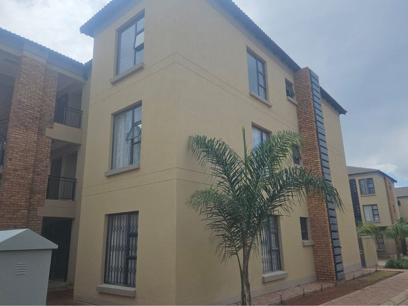 Exterior view of a multi-story apartment building featuring a combination of plastered walls, brick accents, and security bars on the windows.